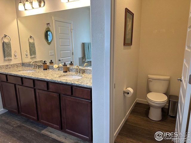 bathroom featuring toilet, vanity, and wood-type flooring