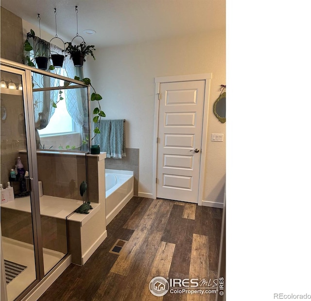 bathroom featuring hardwood / wood-style floors and plus walk in shower