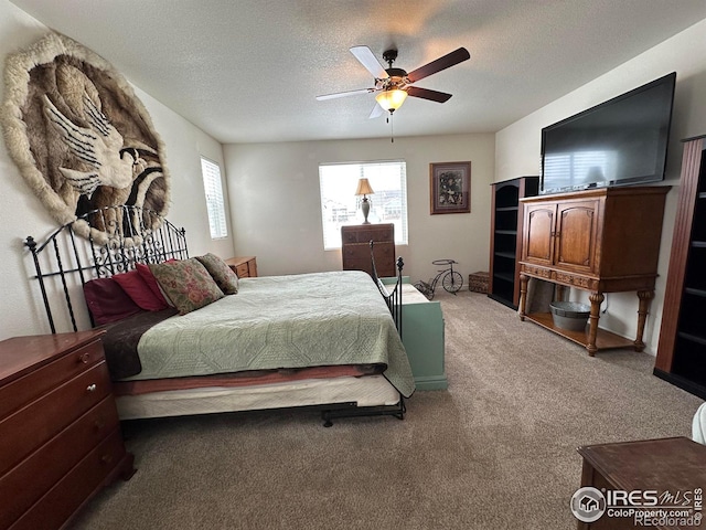 carpeted bedroom with ceiling fan and a textured ceiling