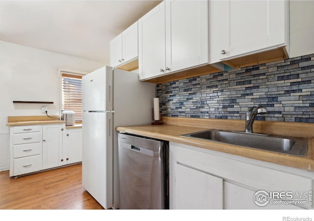 kitchen with stainless steel dishwasher, white cabinetry, sink, and light wood-type flooring