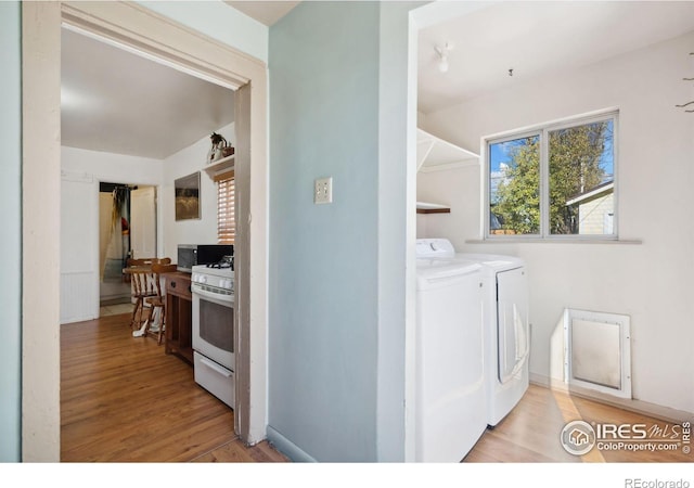 washroom with washing machine and dryer and light hardwood / wood-style floors