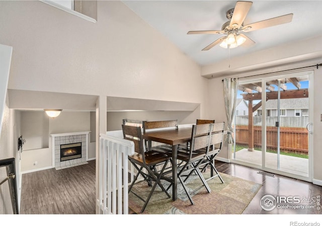 dining room featuring a fireplace, lofted ceiling, dark hardwood / wood-style floors, and ceiling fan