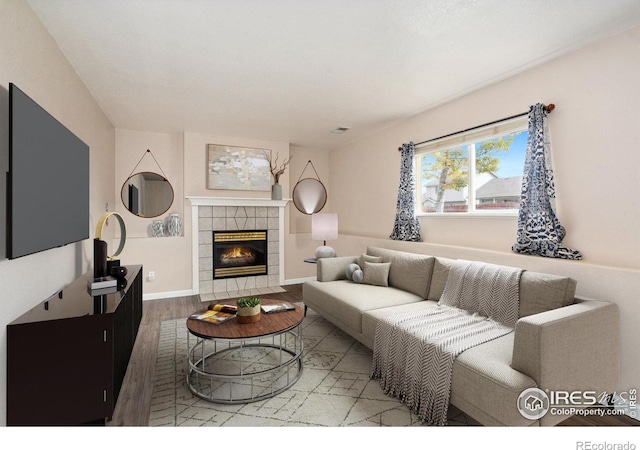 living room featuring wood-type flooring and a tile fireplace