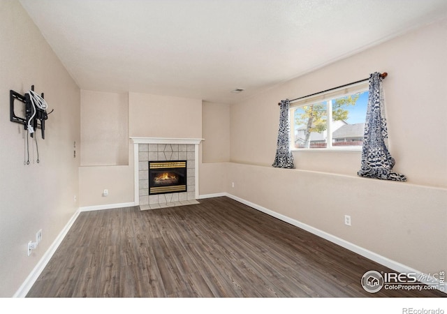 unfurnished living room with dark hardwood / wood-style flooring and a tile fireplace