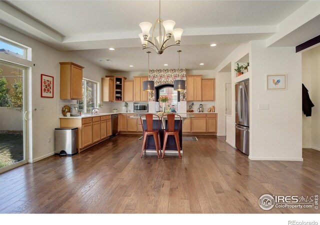 kitchen featuring decorative backsplash, stainless steel appliances, hardwood / wood-style flooring, and decorative light fixtures