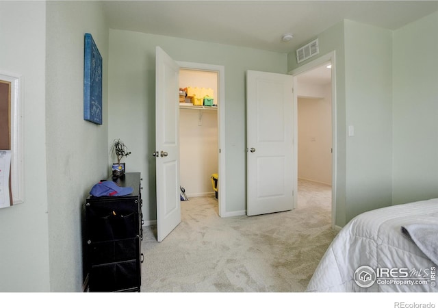 bedroom with a spacious closet, light carpet, and a closet