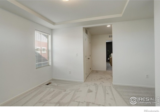 carpeted empty room featuring a tray ceiling