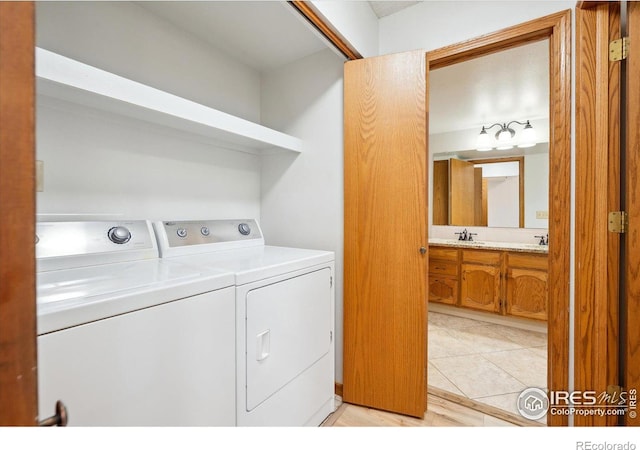 washroom with washing machine and dryer, light tile patterned floors, and sink