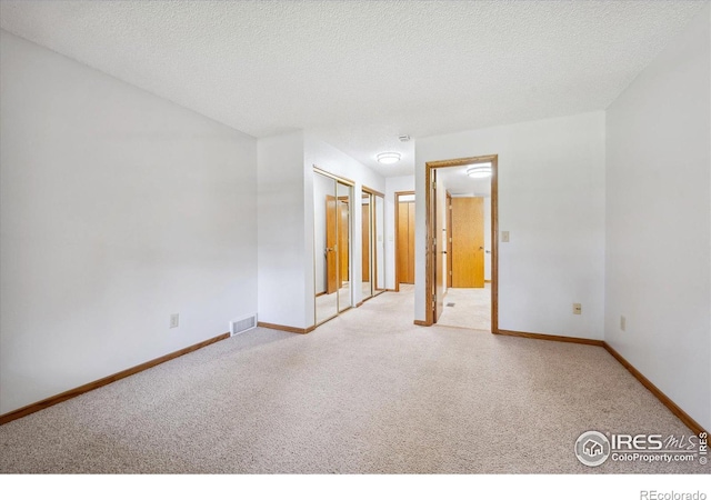 carpeted empty room featuring a textured ceiling