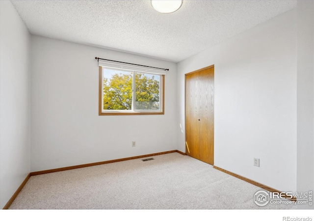 unfurnished room with a textured ceiling and carpet flooring