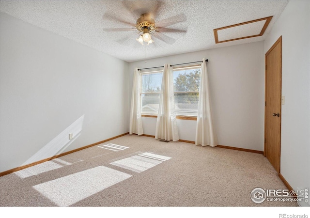 empty room with ceiling fan, light colored carpet, and a textured ceiling