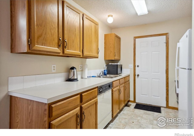 kitchen with a textured ceiling, white appliances, and sink