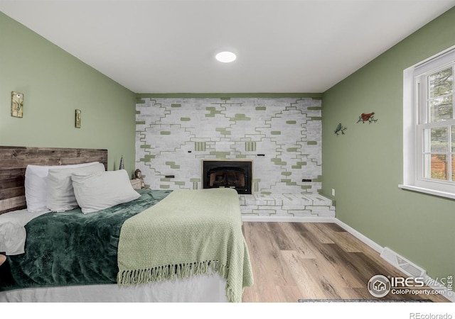 bedroom featuring a large fireplace and light wood-type flooring