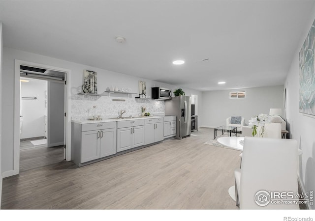 kitchen with stainless steel appliances, gray cabinets, decorative backsplash, sink, and light hardwood / wood-style floors