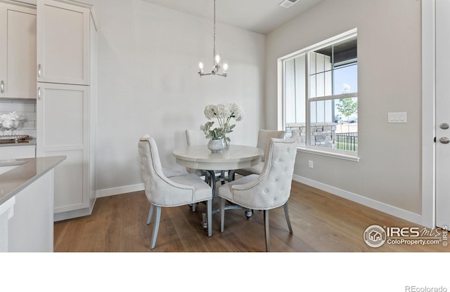 dining space featuring hardwood / wood-style flooring and an inviting chandelier