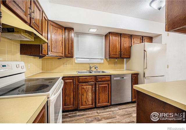 kitchen with a textured ceiling, decorative backsplash, sink, light hardwood / wood-style floors, and white appliances