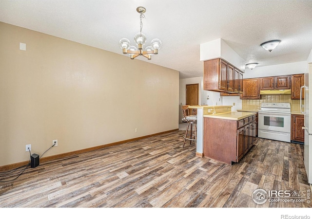 kitchen with dark hardwood / wood-style flooring, white range with electric cooktop, a kitchen breakfast bar, backsplash, and decorative light fixtures