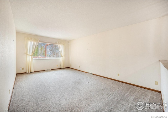 carpeted spare room with a textured ceiling