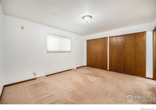 unfurnished bedroom with light colored carpet and a textured ceiling