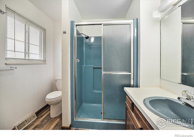 bathroom featuring hardwood / wood-style floors, a shower with shower door, vanity, and toilet