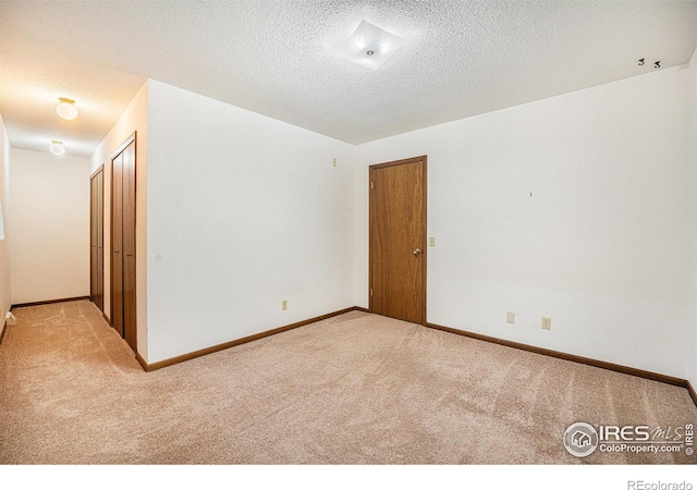 unfurnished room featuring light colored carpet and a textured ceiling