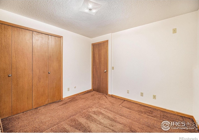 unfurnished bedroom featuring a textured ceiling, light carpet, and a closet