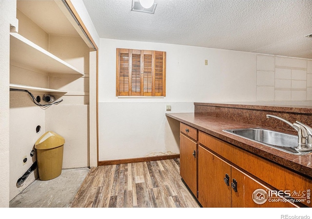 kitchen featuring a textured ceiling, light hardwood / wood-style flooring, and sink