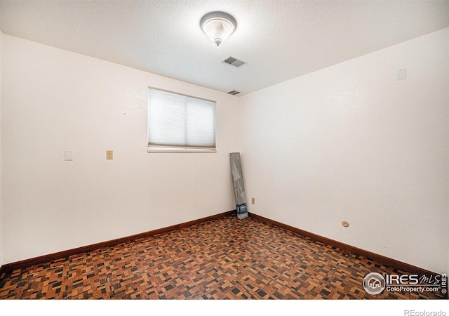 unfurnished room with dark parquet floors and a textured ceiling