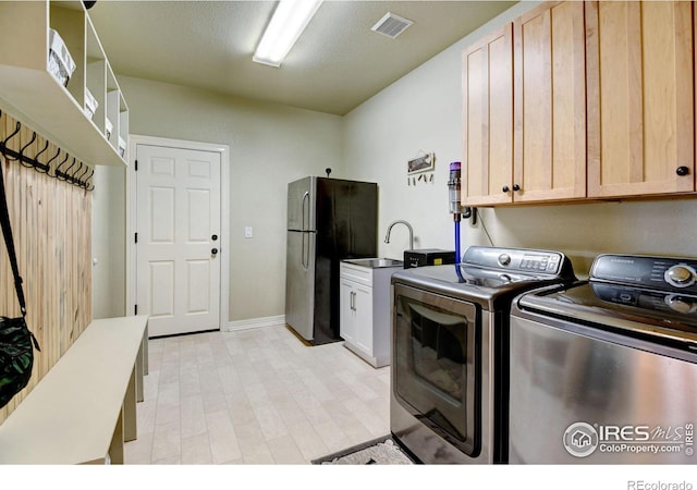 washroom with washing machine and dryer, cabinets, sink, and a textured ceiling