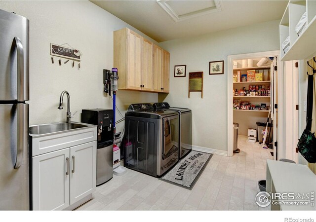 clothes washing area with cabinets, sink, and washer and dryer