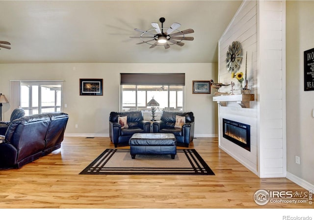 living room featuring a fireplace, ceiling fan, light wood-type flooring, and lofted ceiling