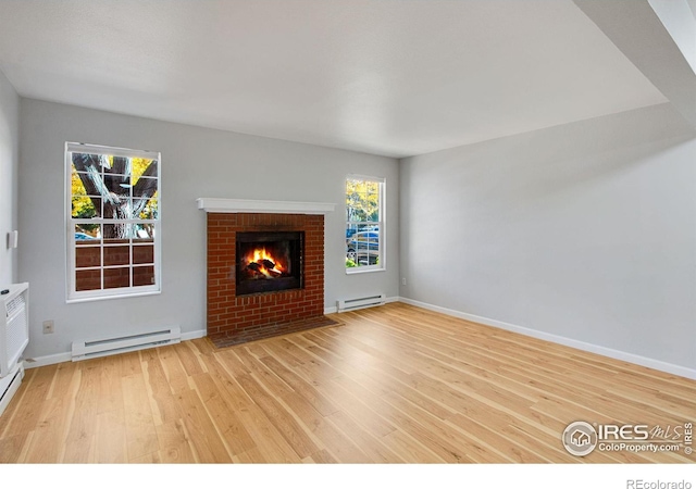 unfurnished living room with baseboard heating, light hardwood / wood-style flooring, and a fireplace