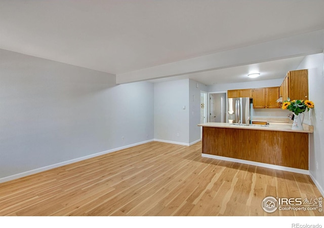 kitchen featuring stainless steel fridge, light hardwood / wood-style flooring, and kitchen peninsula