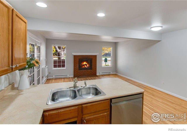 kitchen with sink, light hardwood / wood-style flooring, dishwasher, and a fireplace