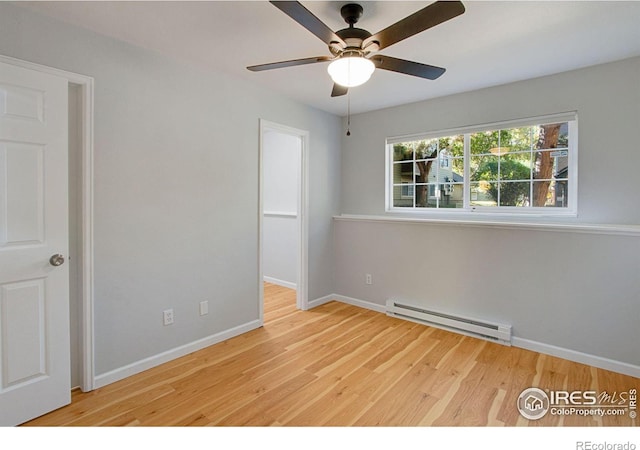 spare room featuring a baseboard heating unit, light wood-type flooring, and ceiling fan