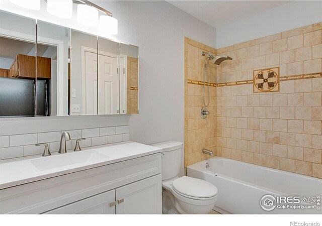 full bathroom with toilet, tiled shower / bath, tasteful backsplash, and vanity