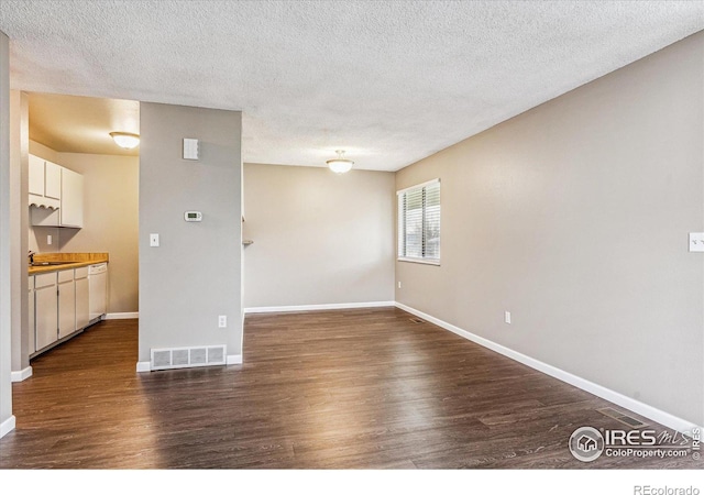 unfurnished living room featuring dark wood-type flooring and a textured ceiling