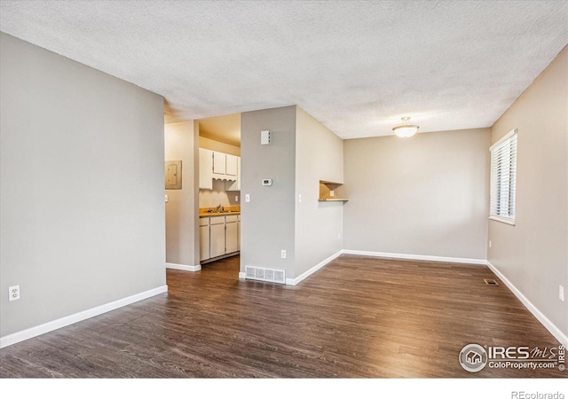 unfurnished room featuring dark wood-type flooring, a textured ceiling, and sink