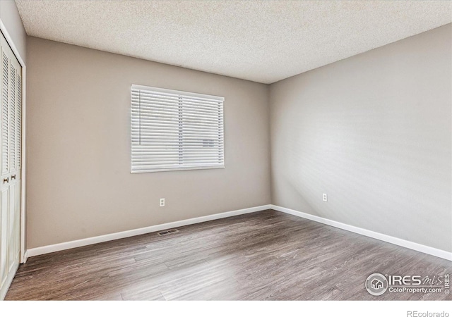 unfurnished bedroom with a textured ceiling, hardwood / wood-style flooring, and a closet