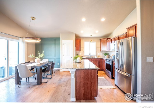 kitchen with stainless steel appliances, lofted ceiling, decorative light fixtures, and a kitchen island