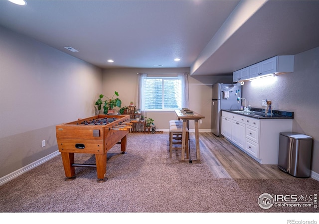 recreation room featuring light carpet and sink