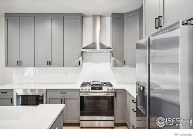 kitchen with stainless steel appliances, wall chimney exhaust hood, and gray cabinetry