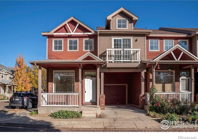 818 S Terry St Unit 85, Longmont, CO 80501 - view of front of house with a porch, a garage, brick siding, a balcony, and driveway