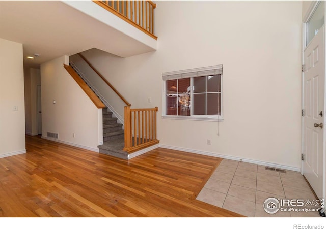 entryway with light hardwood / wood-style floors and a towering ceiling