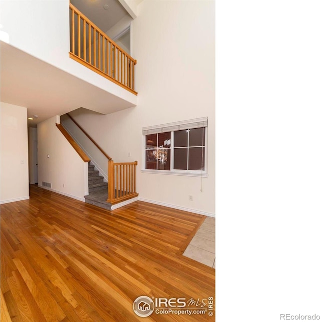 818 S Terry St Unit 85, Longmont, CO 80501 - unfurnished living room featuring stairway, a towering ceiling, wood finished floors, and baseboards
