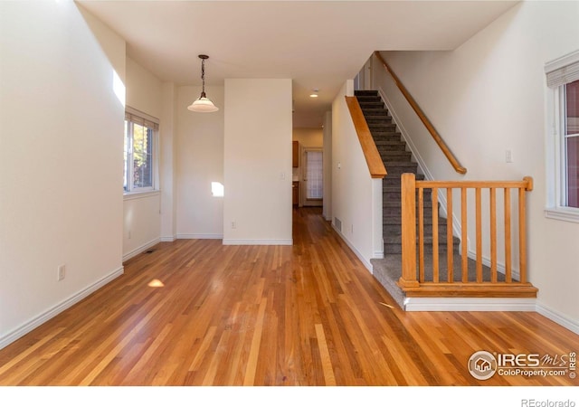 818 S Terry St Unit 85, Longmont, CO 80501 - unfurnished living room with stairway, light wood-style floors, and baseboards