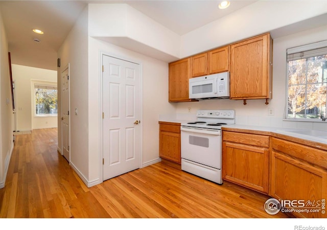 kitchen with white appliances, sink, and light hardwood / wood-style floors