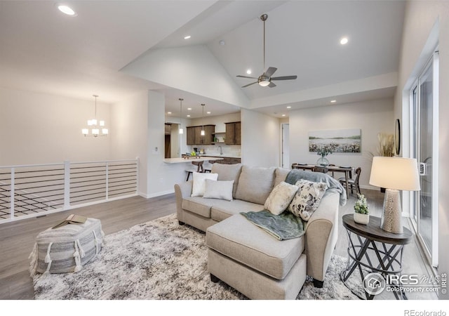 living room with high vaulted ceiling, light wood-type flooring, and ceiling fan with notable chandelier