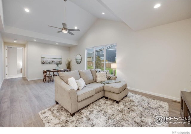 living room with high vaulted ceiling, ceiling fan, and light hardwood / wood-style flooring