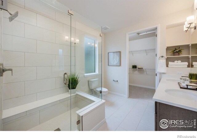 bathroom with a shower with door, vanity, toilet, and tile patterned flooring